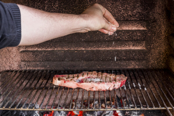 close-up-hand-sprinkling-salt-grilled-beef-barbecue
